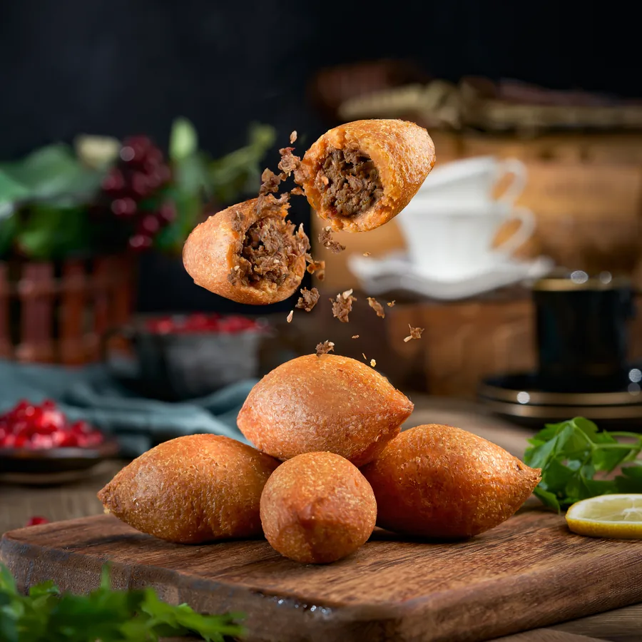 Havada ikiye bölünen içli köfte ve ahşap tahtada içli köfteler, yemek fotoğrafı
