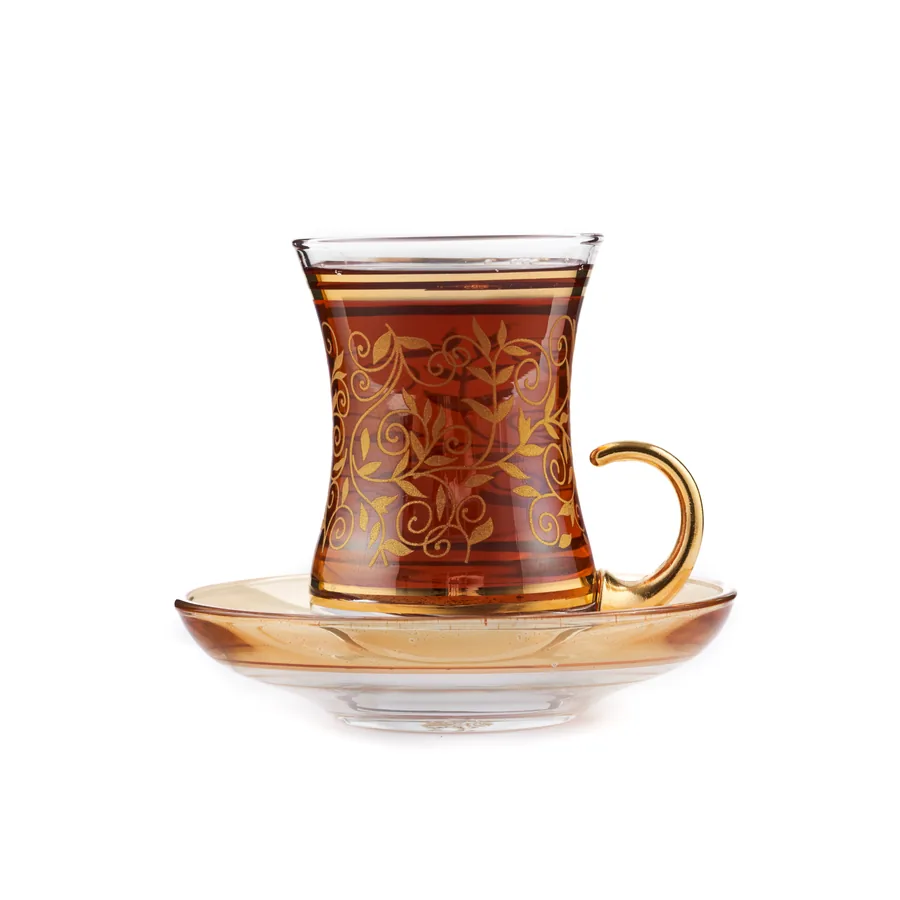 Altın desenli çay bardağı ve tabağı, beyaz fonda