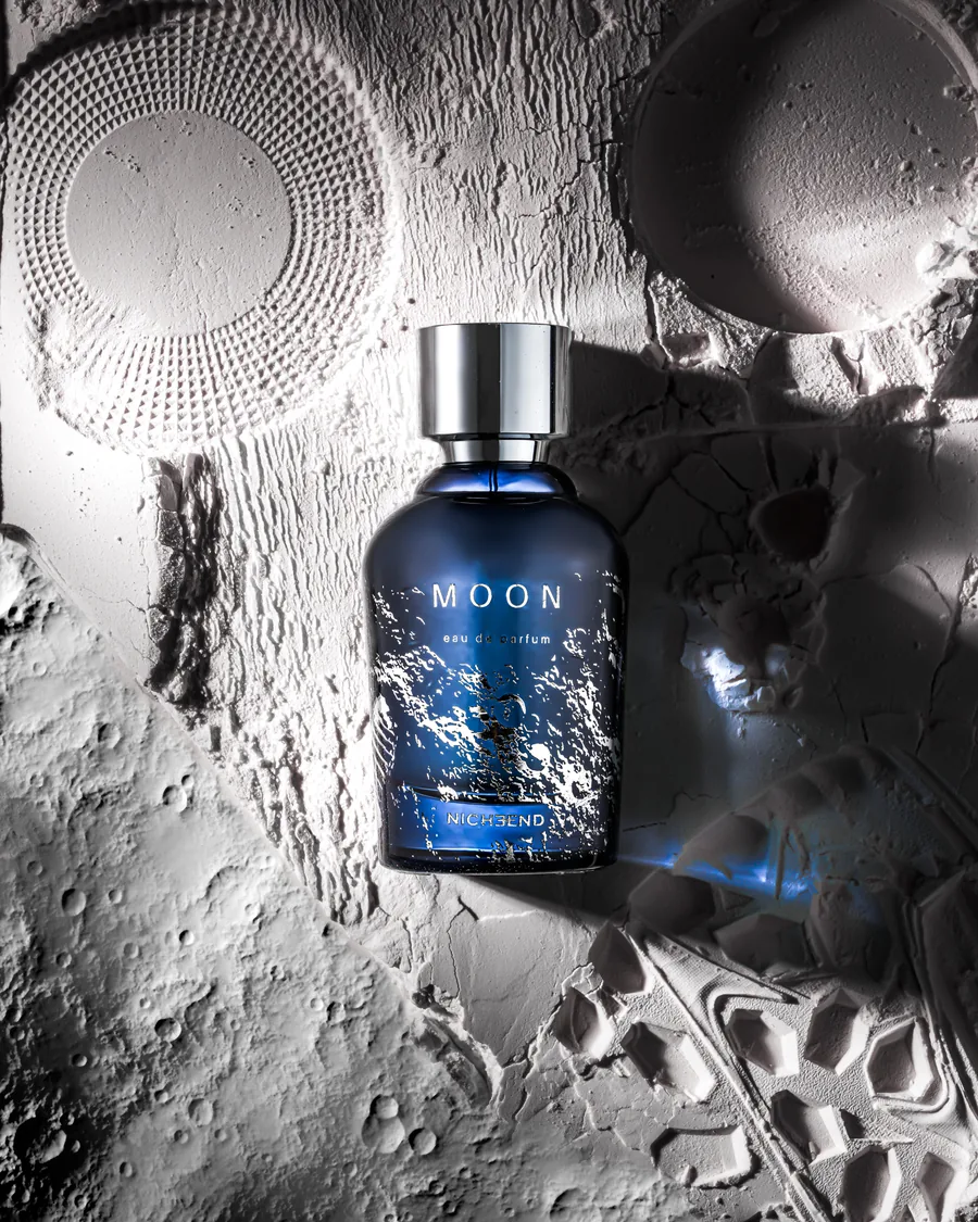 Ay yüzeyini andıran dokulu zeminde MOON parfüm şişesi